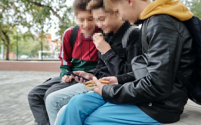 Drei Jugendliche amüsieren sich über die Bilder auf ihrem Smartphone
