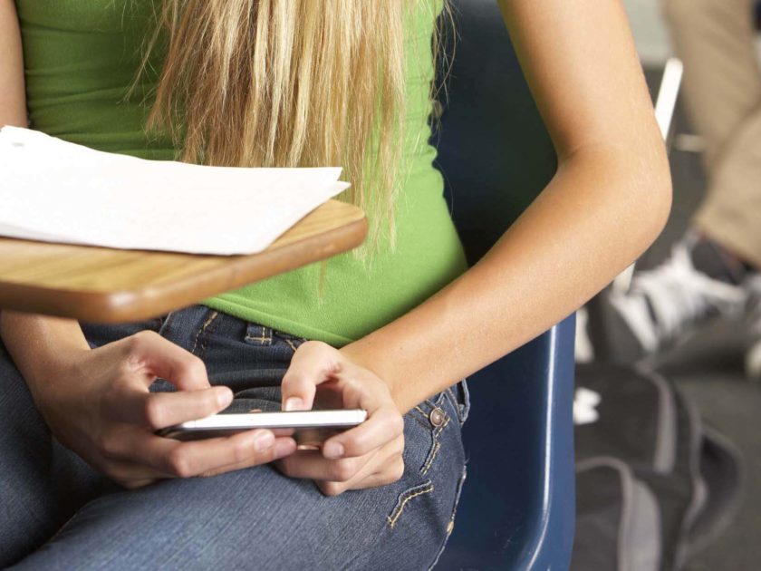 Eine Schülerin nutzt heimlich ihr Handy während einer Klassenarbeit
