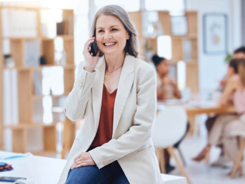 eine ältere Dame telefoniert. Ihr team arbeitet im Hintergrund