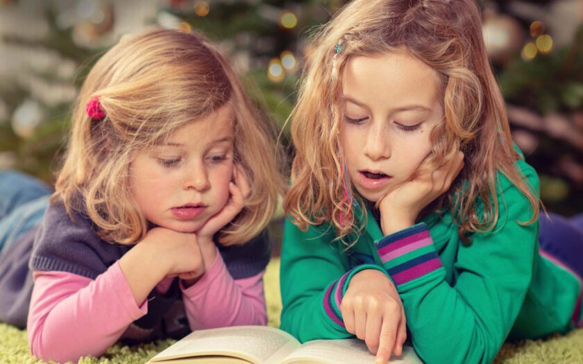 2 Mädchen lesen in einem dicken Buch