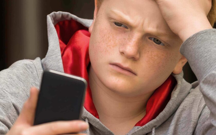 Junge schaut traurig auf sein Handy