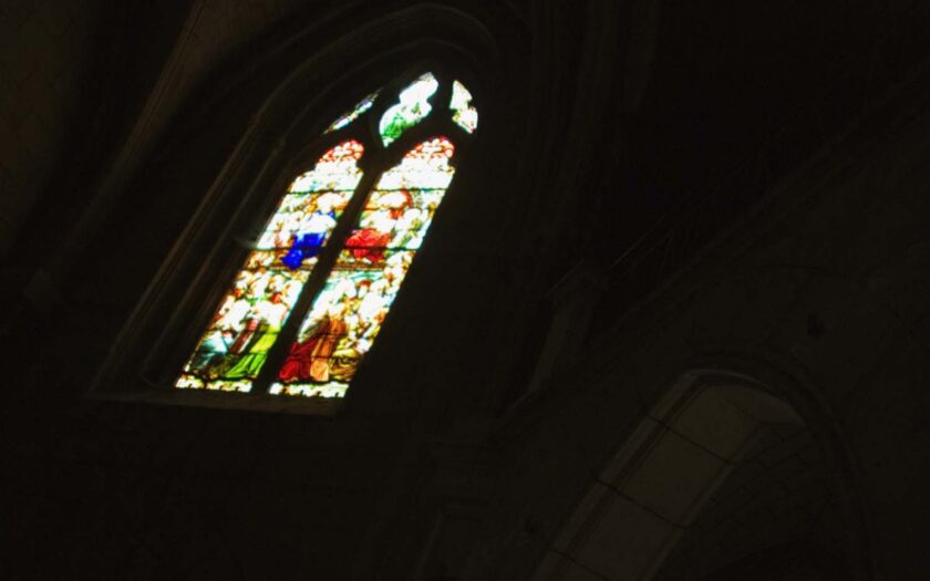 Kirchenfester in einer dunklen Kirche als Symbol für sexuellen Missbrauch